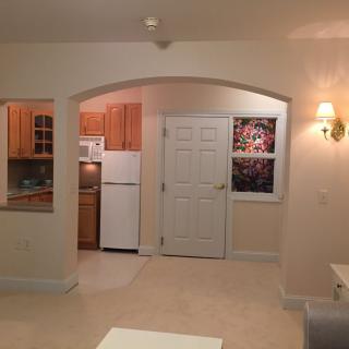 A cozy apartment interior featuring a kitchen and living area with warm lighting.