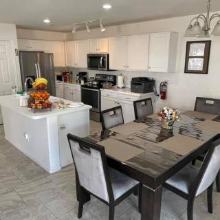 A modern kitchen and dining area with white cabinets, a kitchen island, and a wooden dining table.
