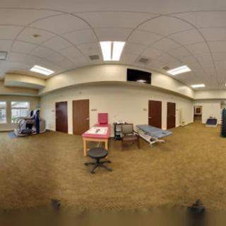 A spacious therapy room with exercise equipment and medical beds, designed for rehabilitation purposes.