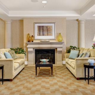 Cozy living room with beige sofas and a central fireplace.