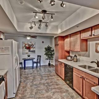 A modern kitchen with wooden cabinets, track lighting, and a small dining area.