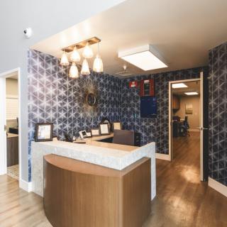 A modern reception area with a wooden desk and patterned wallpaper.