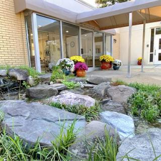 A serene outdoor space featuring a rock garden and vibrant flowers by the entrance.