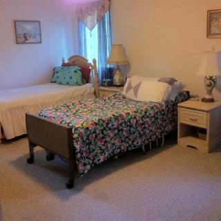 A cozy bedroom featuring two beds, each with decorative bedding, accompanied by nightstands and lamps.