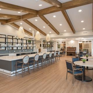 A modern interior featuring a bar and dining area with elegant wooden beams and pendant lighting.