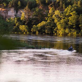 A serene moment on the river as a motorboat glides through the water surrounded by lush greenery.