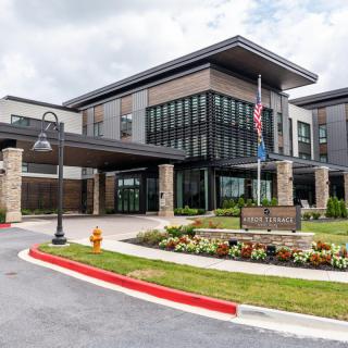 A modern building with large windows and a landscaped entrance.