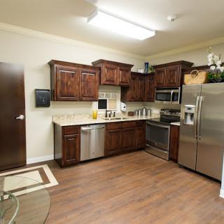 A modern kitchen with wooden cabinets, stainless steel appliances, and hardwood flooring.