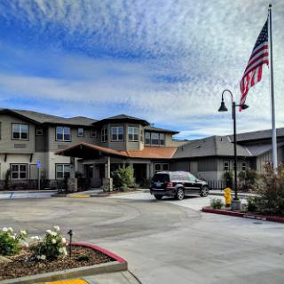 A picturesque residential building with an American flag flying in the foreground, set against a cloudy sky.
