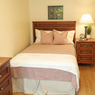 A cozy bedroom with a neatly made bed, nightstands, and a lamp providing soft lighting.