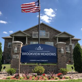 Brookview Meadows apartment building with an American flag and garden in front.