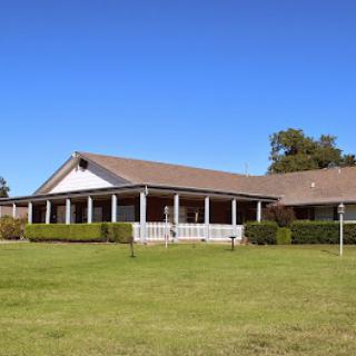 A charming house set against a clear blue sky, featuring a spacious porch and well-maintained lawn.