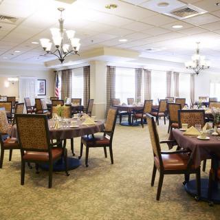 Spacious dining area with neatly arranged tables and elegant chandeliers.