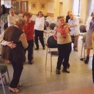 A group of elderly individuals participating in a community exercise session indoors.