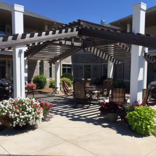 A sunny outdoor patio with a pergola and garden seating area.