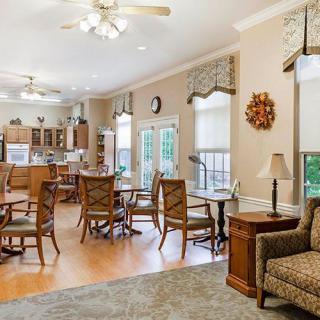 A cozy and well-lit living and dining area with wooden furniture, adjacent to a kitchen.