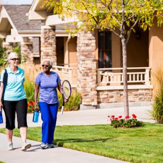 Two friends enjoying a walk in their neighborhood, promoting an active lifestyle.