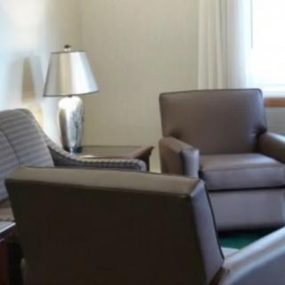 A cozy living room with several comfortable chairs and a lamp.