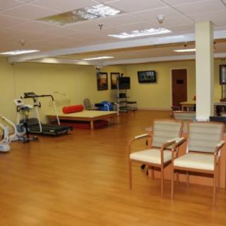 A spacious physical therapy room equipped with various exercise and rehabilitation equipment.