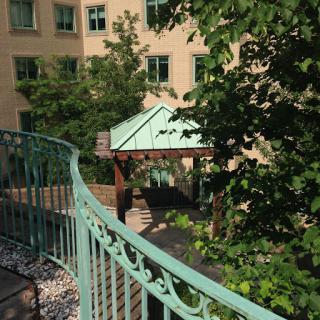 A view of a garden area featuring a gazebo and surrounding greenery, framed by a decorative railing.