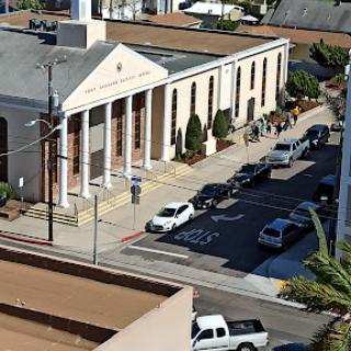 A street view featuring a well-structured building alongside parked cars.