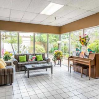 A bright and welcoming lobby area with seating, a piano, and large glass windows overlooking greenery.