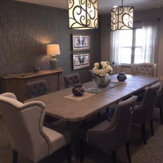A stylish dining room featuring a long table with elegant chairs and modern decorative lighting.