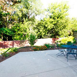 A serene outdoor patio surrounded by lush green trees and a cozy seating area.