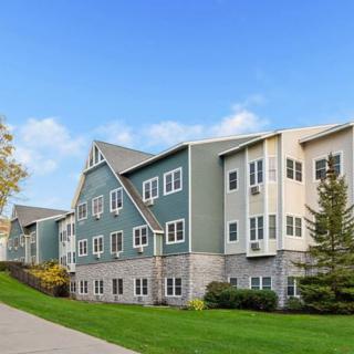 A modern residential apartment building with a scenic landscape and a clear blue sky.