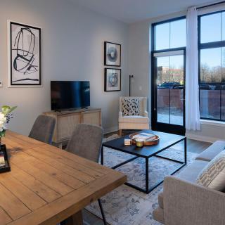 A modern living room with a dining area, featuring stylish decor and large windows.