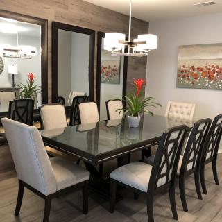 A modern dining room with a glass table, cushioned chairs, and elegant decor.