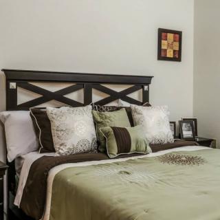 A well-decorated bedroom featuring a comfortable bed with multiple pillows and a stylish headboard.