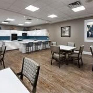 A modern kitchen and dining area with several tables and chairs, featuring bright lighting and contemporary interior design.