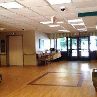 A spacious waiting area in a healthcare facility, featuring an elevator, seating arrangements, and ample natural light.