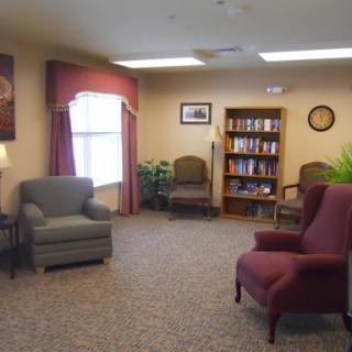 A cozy living room with armchairs, a bookshelf, and decorative elements.