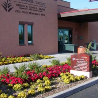 A hospital entrance featuring a well-maintained garden with colorful flowers and clear signage.
