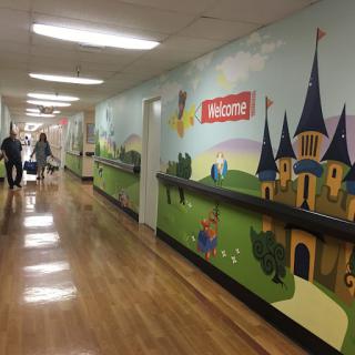 A colorful hallway decorated with a welcoming mural featuring castles and playful scenes, designed to create a friendly atmosphere.