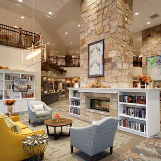 A modern lobby with a cozy seating area featuring a stone fireplace and bookshelves.