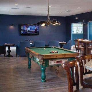 A modern billiard room with a pool table, television, and lounge seating.