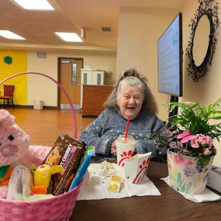 An elderly woman enjoying a cheerful gathering with festive decorations and treats.