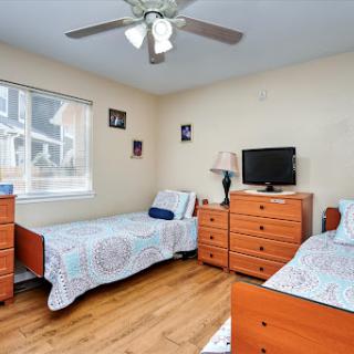 A cozy bedroom featuring twin beds, a ceiling fan, and wooden furniture.