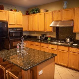 A modern kitchen with wooden cabinets and a granite-topped island.