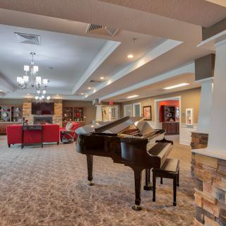 A spacious lounge featuring a grand piano, comfortable seating, and elegant lighting.