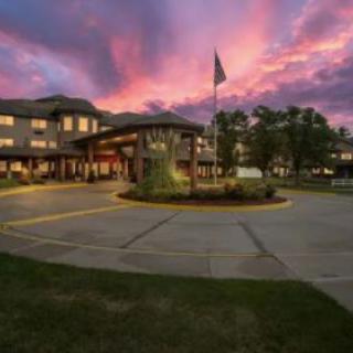 A beautifully lit building at sunset with a dramatic sky and flagpole in the foreground.