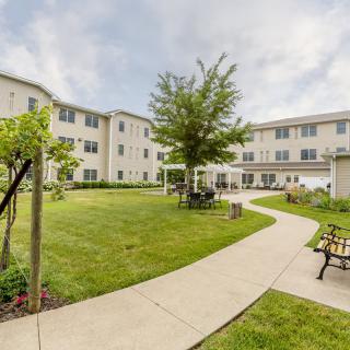 A residential building with a landscaped courtyard featuring a pathway, benches, and greenery.