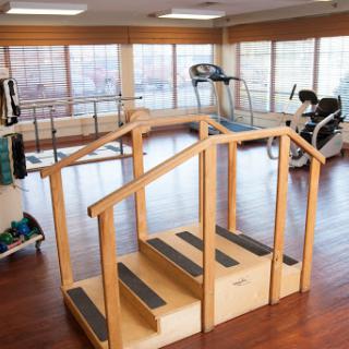 A rehabilitation gym featuring a wooden stair setup, designed for physical therapy and exercise.