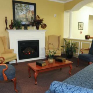 A cozy living room with a fireplace, armchairs, and a coffee table.