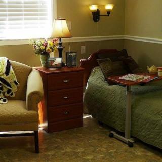 A cozy bedroom with a bed, nightstand, and comfortable chair.