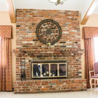 A cozy living room with a large brick fireplace and decorative wall clock.