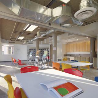 A modern, colorful classroom interior with tables and chairs arranged in an open space.